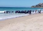 In this image taken from video, migrants scatter as a rubber dingy lands on the beach at Cadiz, southern Spain, Wednesday Aug. 9, 2017. Beachgoers watched as around two dozen suspected migrants scattering on the beach. Disembarkations by migrants on Spanish beaches aren't common but have happened before, especially at Spain's north African enclave cities of Melilla and Ceuta, which border Morocco. (Carlos Sanz via AP)