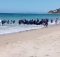 In this image taken from video, migrants scatter as a rubber dingy lands on the beach at Cadiz, southern Spain, Wednesday Aug. 9, 2017. Beachgoers watched as around two dozen suspected migrants scattering on the beach. Disembarkations by migrants on Spanish beaches aren't common but have happened before, especially at Spain's north African enclave cities of Melilla and Ceuta, which border Morocco. (Carlos Sanz via AP)